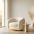 Modern white armchair in a minimalistic room with a small table and decorative elements.