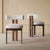 Two wooden chairs with white cushioned seats.