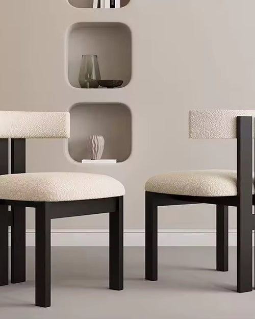 Two modern chairs with black frames and beige cushions.