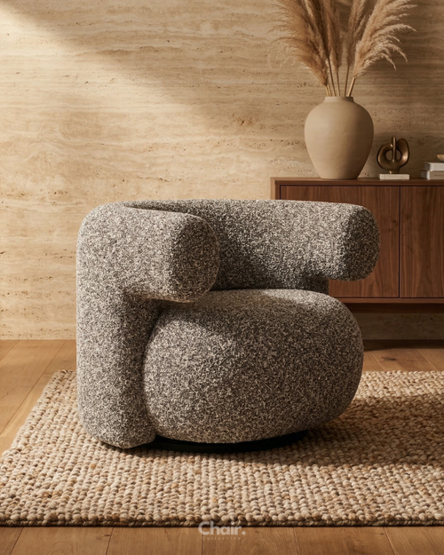 Modern & Luxury chair in a room with wooden floor and wall, and a vase with dried plants on a sideboard.