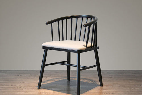 Black-finished teak wood dining chair featuring a curved spindle backrest and upholstered seat, designed for modern dining spaces and hospitality interiors.