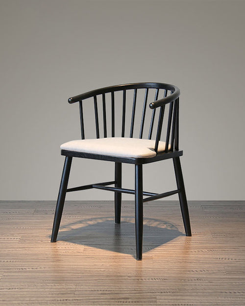 Black-finished teak wood dining chair featuring a curved spindle backrest and upholstered seat, designed for modern dining spaces and hospitality interiors.