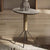 Small round table with a marble top and cylindrical base on a wooden floor.