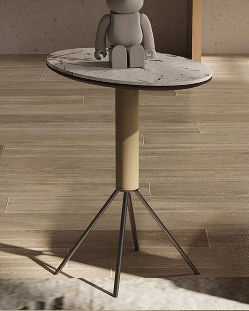 Small round table with a marble top and cylindrical base on a wooden floor.