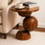 Sculptural end table crafted entirely from solid teak wood, featuring rounded geometric forms and a circular tabletop for contemporary luxury interiors.