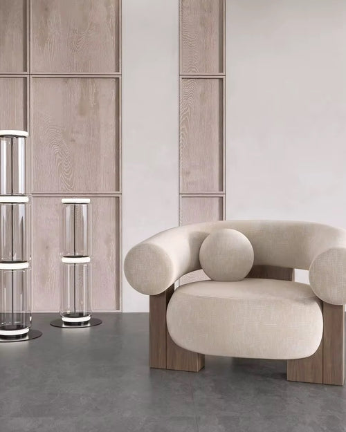 The Nomad Chair blends organic curves with architectural precision, creating a piece that feels both grounded and ethereal. Its rounded, cloud-like seat and armrests rest upon solid wood block legs, offering a harmonious balance of softness and strength.