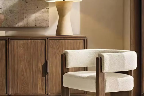 The Orion Chair embodies a perfect interplay of geometry and comfort, designed to be both sculptural and inviting. Its bold wooden legs rise seamlessly into the frame, grounding the design with architectural strength, while the plush bouclé upholstery wraps the seat and backrest in understated luxury.