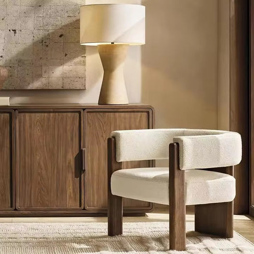 The Orion Chair embodies a perfect interplay of geometry and comfort, designed to be both sculptural and inviting. Its bold wooden legs rise seamlessly into the frame, grounding the design with architectural strength, while the plush bouclé upholstery wraps the seat and backrest in understated luxury.