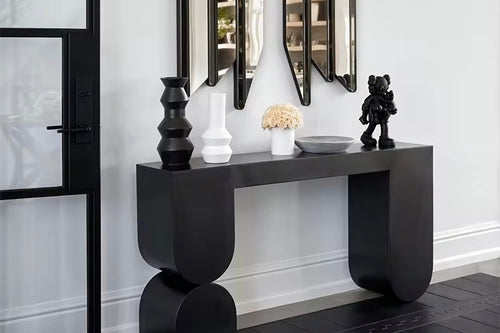 The Noir Console is a striking fusion of contemporary design and sculptural artistry. Crafted with clean lines and bold geometric shapes, it features a deep matte black finish that adds drama and sophistication to any interior. Its sleek form and strong presence make it a perfect statement piece for entryways, living rooms, or hallways where modern elegance and functional style are key.
