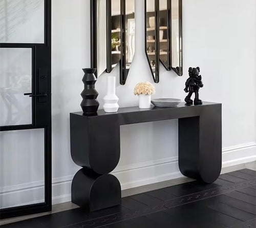 The Noir Console is a striking fusion of contemporary design and sculptural artistry. Crafted with clean lines and bold geometric shapes, it features a deep matte black finish that adds drama and sophistication to any interior. Its sleek form and strong presence make it a perfect statement piece for entryways, living rooms, or hallways where modern elegance and functional style are key.