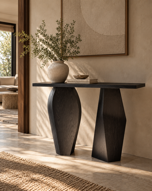 Junto Foyer Console by Chair Collective featuring a dark smoked black ash finish, natural wood texture, and contrasting sculptural pedestal legs in a contemporary entryway.