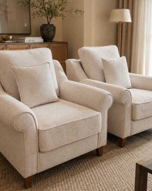 A luxurious upholstered accent chair featuring plush cushions, elegant rolled arms, a supportive backrest, and solid wooden legs designed for comfortable everyday living.