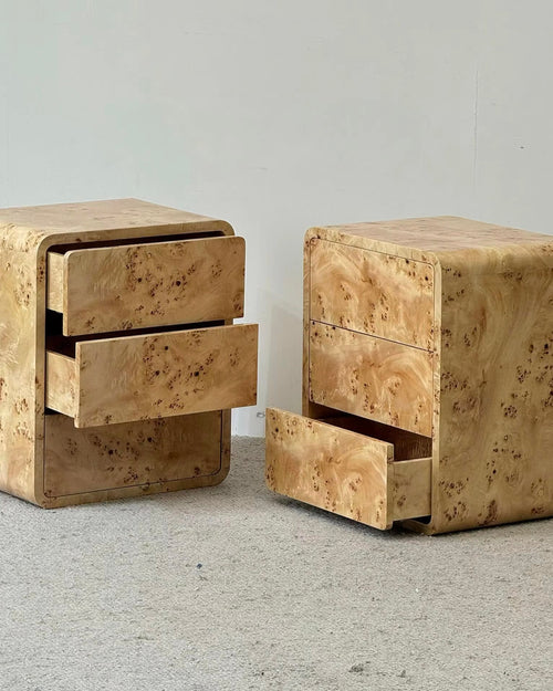  nightstands with three drawers each, featuring a distinctive light tan burl wood grain finish, shown on a light gray carpet against a plain wall.