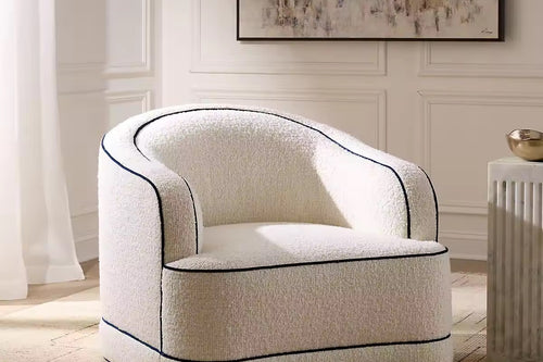 Modern upholstered accent chair featuring a sculptural curved silhouette, rounded arms, plush seating, and contrasting double piping detail.