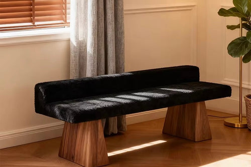 Contemporary wooden ottoman featuring a long upholstered seat and sculptural wooden legs, designed for bedrooms, living rooms and luxury interiors.