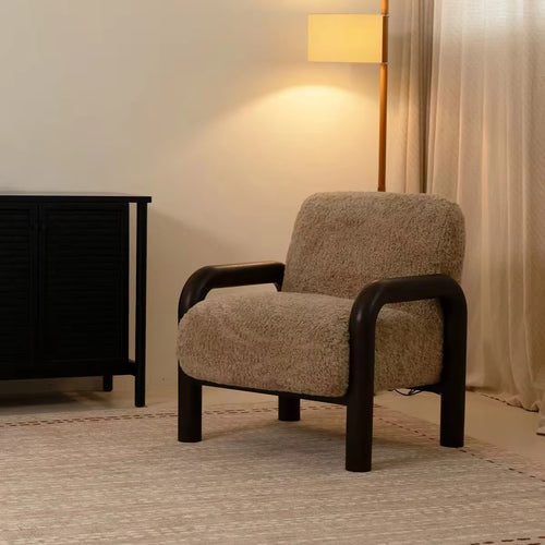 Rico Accent Chair featuring a warm textured upholstered seat and backrest, sculptural dark wooden curved arms, and a sturdy wooden frame with an architectural silhouette.