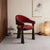 Yondu Dining Chair featuring a curved red upholstered seat and back, sculptural wooden arms, and a dark wood frame designed for contemporary dining spaces.