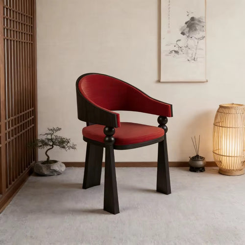 Yondu Dining Chair featuring a curved red upholstered seat and back, sculptural wooden arms, and a dark wood frame designed for contemporary dining spaces.