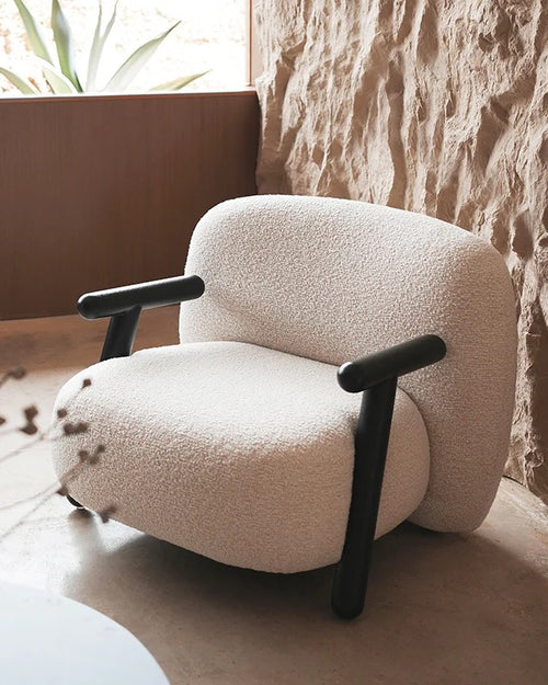 Upholstered in plush, textured fabric, the Zedd Lounge Chair invites you to slow down and sink in. Its generously rounded seat and gently contoured backrest create a cocooning experience, while the striking wooden arms add contrast, strength, and architectural presence. Every detail reflects thoughtful craftsmanship, making it a statement chair that elevates modern Indian interiors.